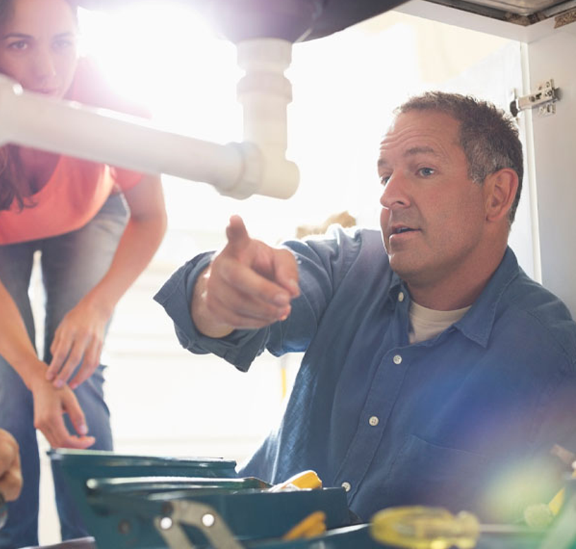 Professional plumber repairing copper pipes beneath a kitchen sink